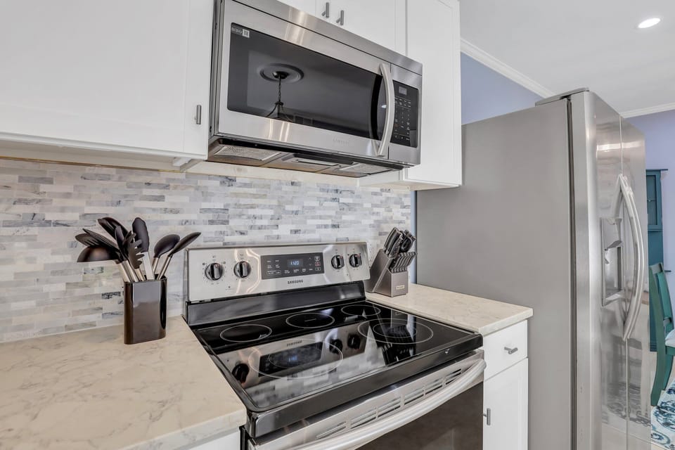 Fully stocked kitchen with stainless steel appliances and 2 barstools for extra seating