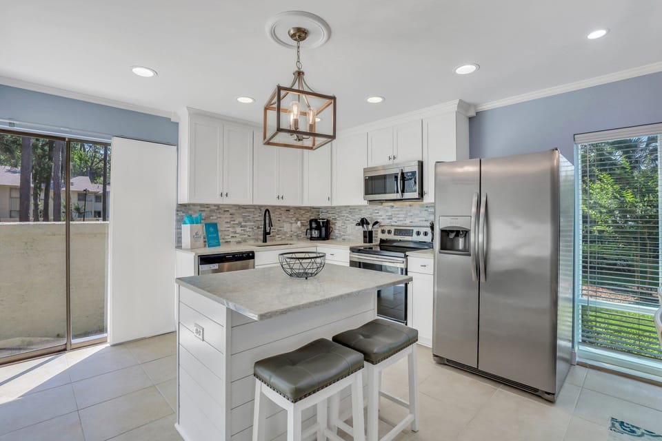Fully stocked kitchen with stainless steel appliances and 2 barstools for extra seating