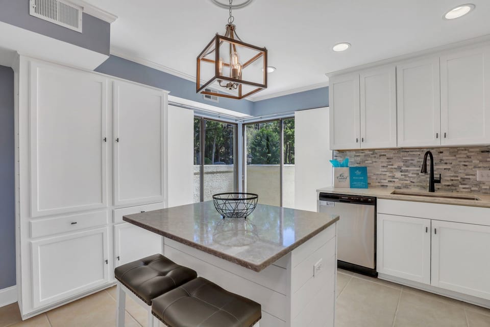 Fully stocked kitchen with stainless steel appliances and 2 barstools for extra seating