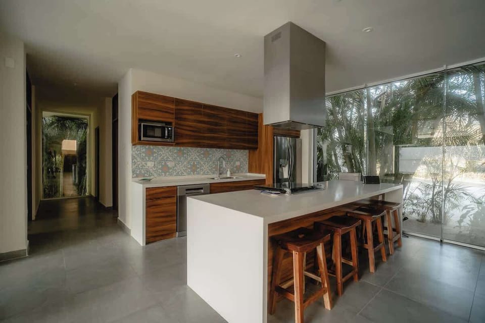 Open concept, newly remodeled kitchen with gas oven and stove built into the island. 4 barstools, dishwasher, microwave, blender, drip coffee machine, toaster, filtered water with 3 instant temperature options, cooking equipment and dishes.