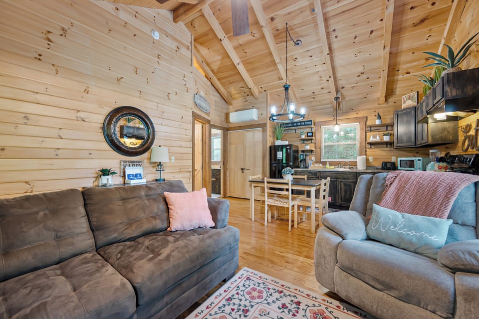 Inviting open-concept living and dining area with vaulted wood ceilings and comfy couches.