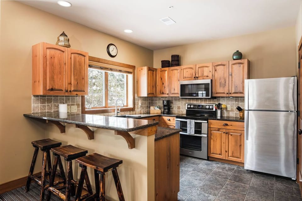 Fully stocked kitchen with rustic bar stools & stainless steel appliances