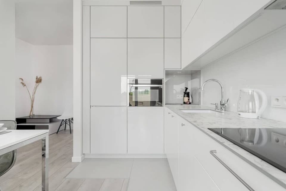 The fully equipped kitchenette includes an induction hob, a combination oven with microwave function, a fridge, and ample cabinet space.