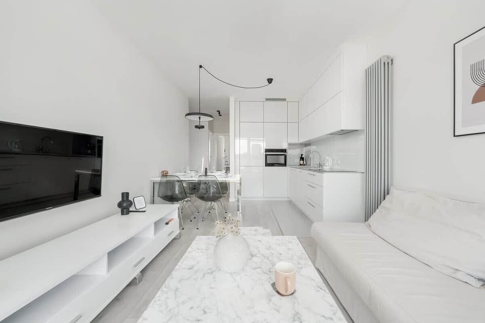 Living room with fold-out sofa bed, TV and kitchenette with dining area.