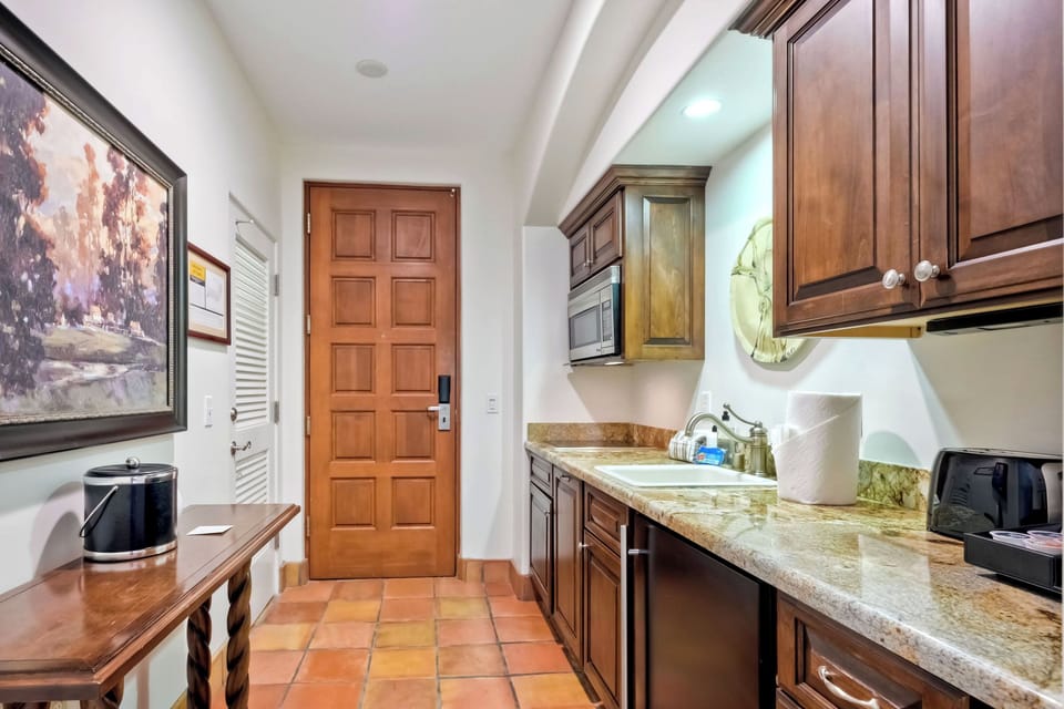 Galley kitchen with electric range, mini fridge, microwave, and more.