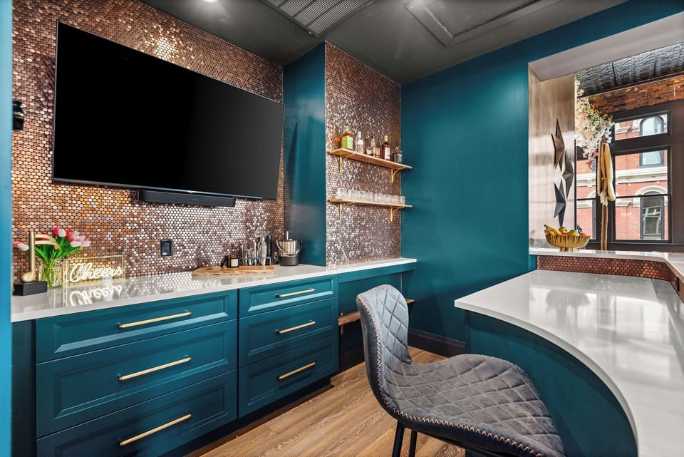 - Bar counter with penny-tile backsplash and glowing lighting   - Teal cabinets and wood shelves create a bold modern look   - Stylish setup ideal for mixing drinks and enjoying the space