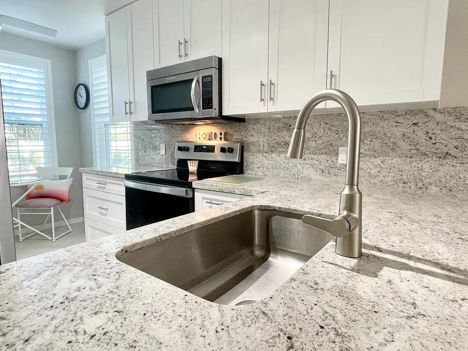 Kitchen featuring quartz countertops, Shaker cabinets, and stainless steel appl.