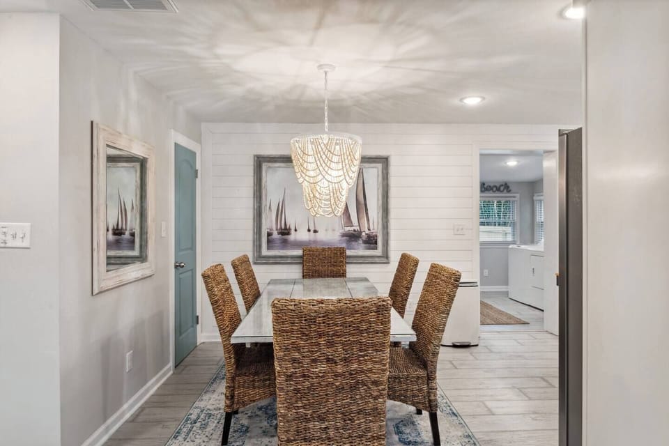  This inviting dining area provides the perfect space for cozy meals and social connection.  The comfortable table comfortably seats six guests, fostering conversation and laughter.  The charming chandelier adds a touch of warmth and ambiance to the space.  This haven is perfect for enjoying everyday meals or hosting special occasions with loved ones.