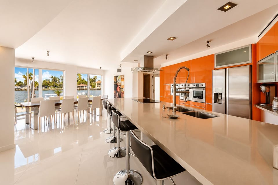 Modern waterfront kitchen with oversized island and sunlit dining area