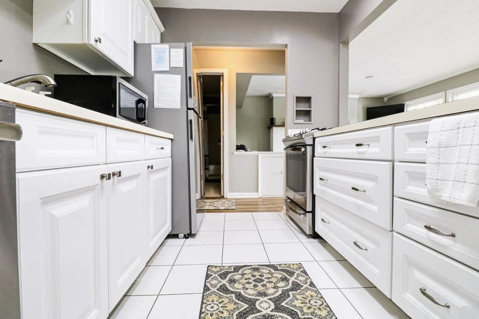 Sleek galley kitchen w/ white cabinetry, modern appliances & patterned tile accents.