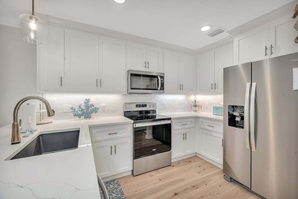 White kitchen with stainless range, refrigerator, and sink