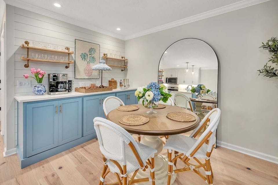 Dining area with blue cabinets, round table, and arched mirror