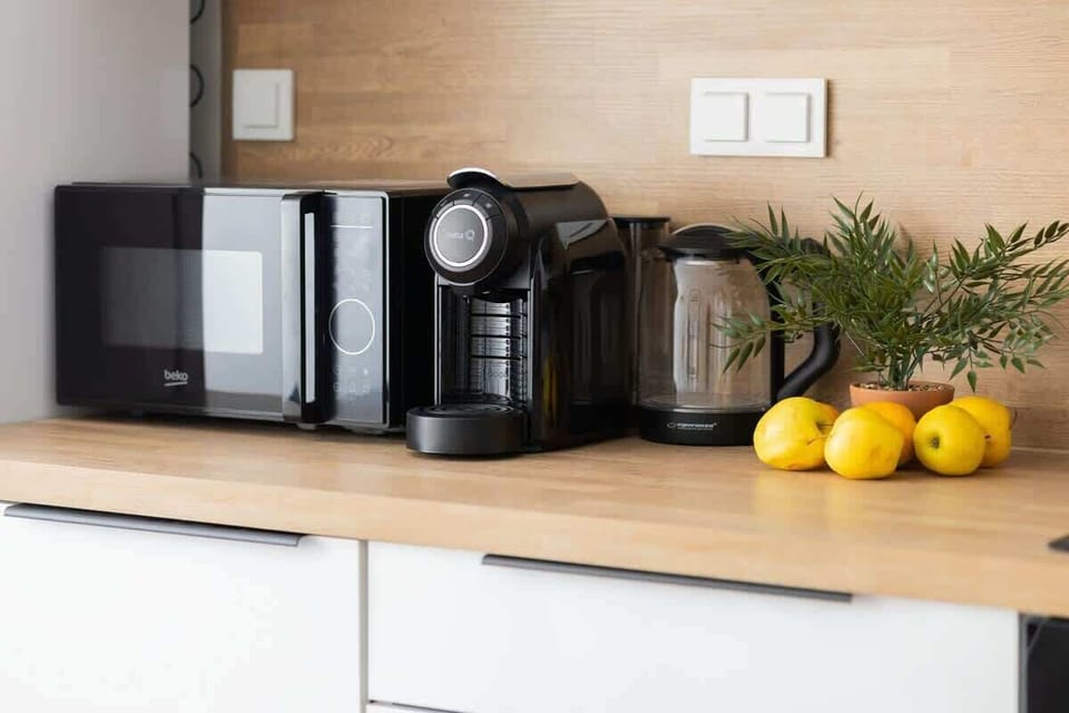 A close-up of a kitchen counter, featuring a modern coffee machine and a decorative arrangement with lemons and small plants for a fresh touch.