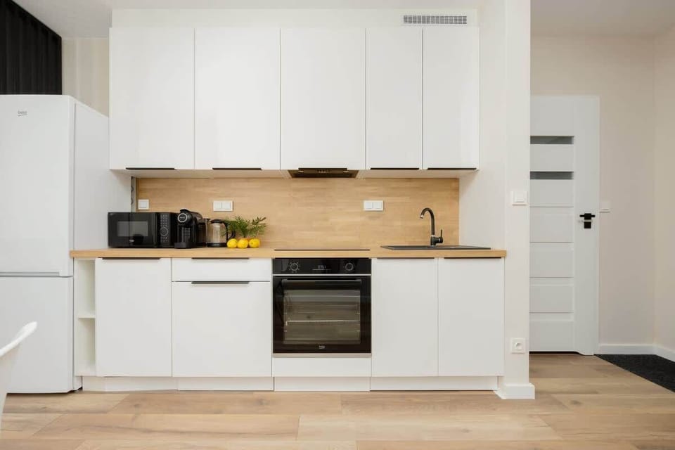 A stylish, well-organized kitchen with white cabinets, a built-in oven, and a bright wood countertop, perfectly blending modern functionality and design.