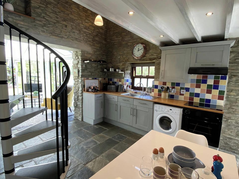 kitchen area with kitchen table, washing machine, kettle , toaster, oven and extractor hood.