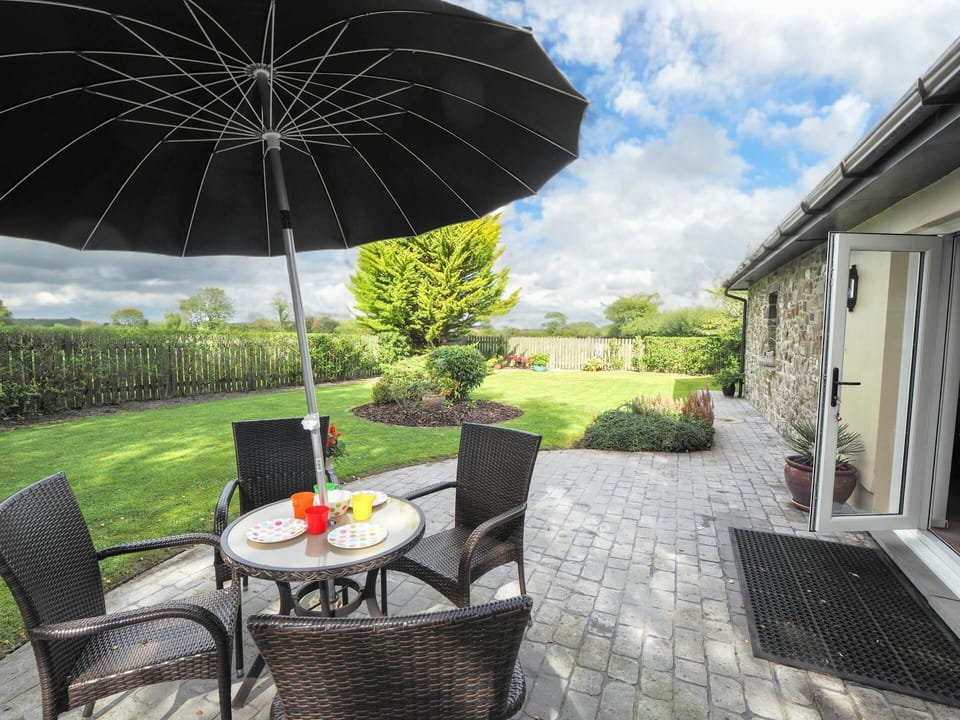 Doors leading from sitting room to patio area with circular table, four chairs and parasol