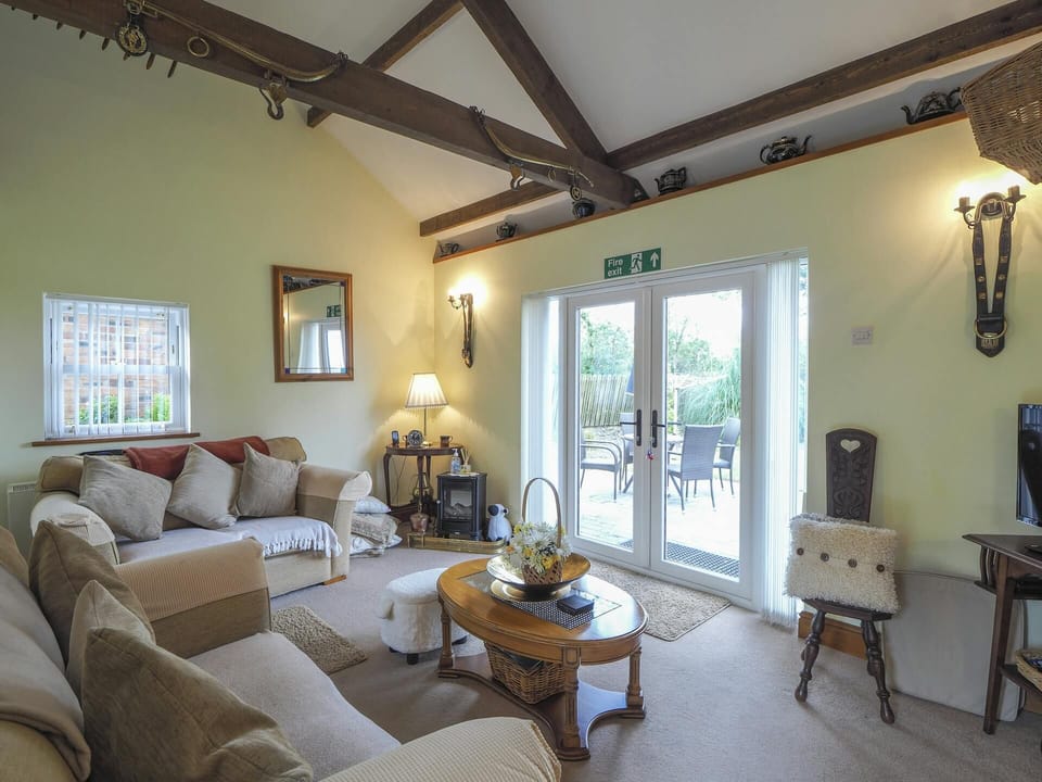 Two sofas, coffee table, corner table with lamp and patio doors leading to garden