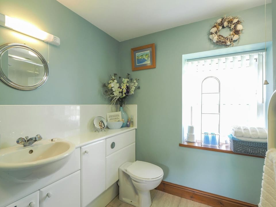 Bathroom with WC, wash hand basin and mirror over. Built in storage cupboards