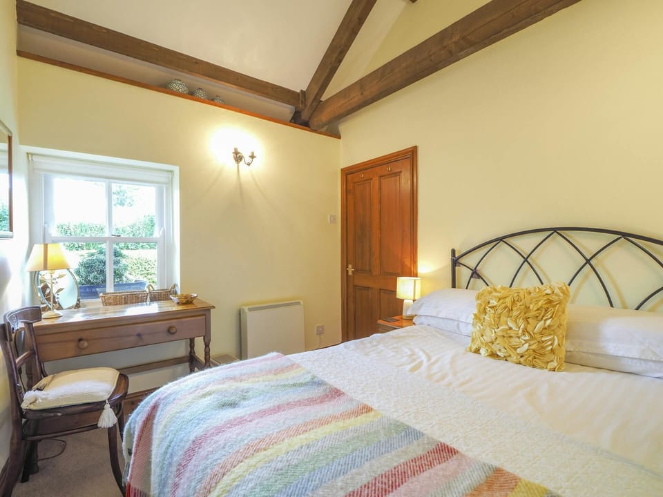 Double bed, dressing table and chair. Window overlooking the garden
