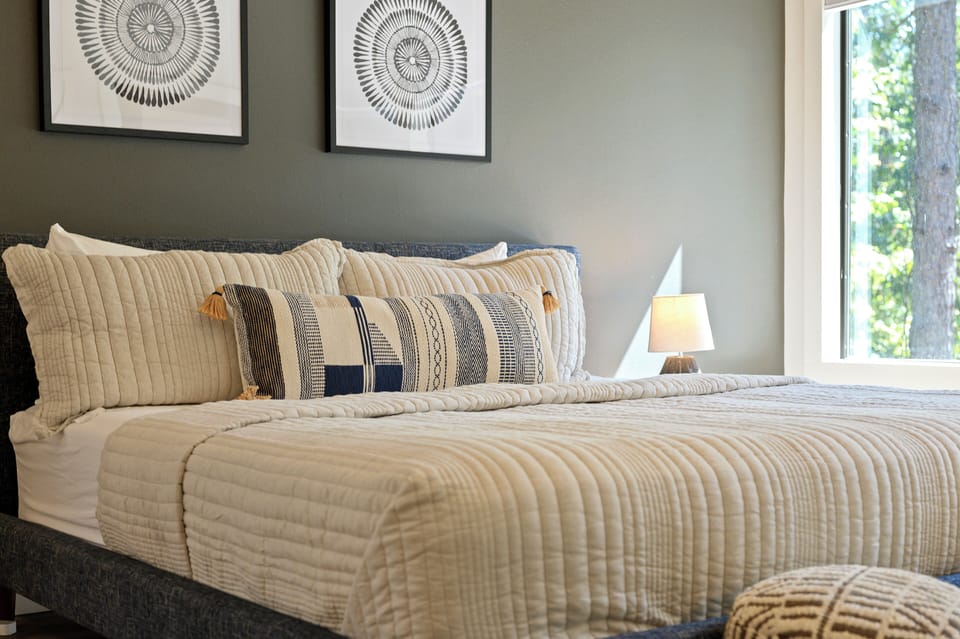 Retreat to your cozy king bedroom with calming tones and a view of the pines from the window.