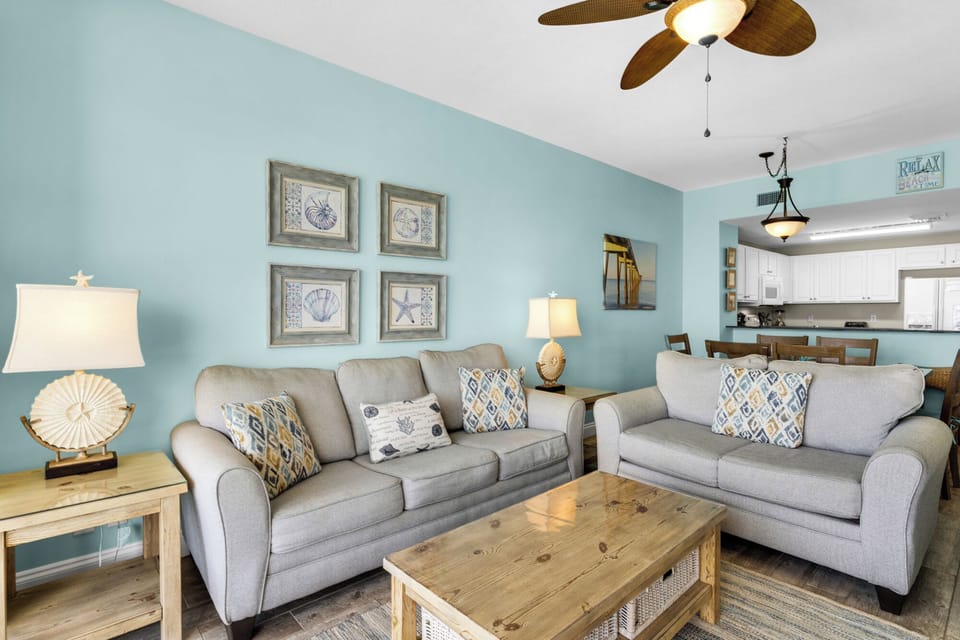 Living Room - Relax in this coastal living space featuring a large flat-screen TV, beautiful decor, and a private balcony with breathtaking beach views.