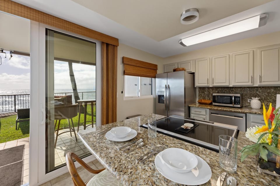 Prepare meals while enjoying breathtaking ocean views from this fully stocked kitchen, complete with sleek granite countertops and stainless steel appliances.