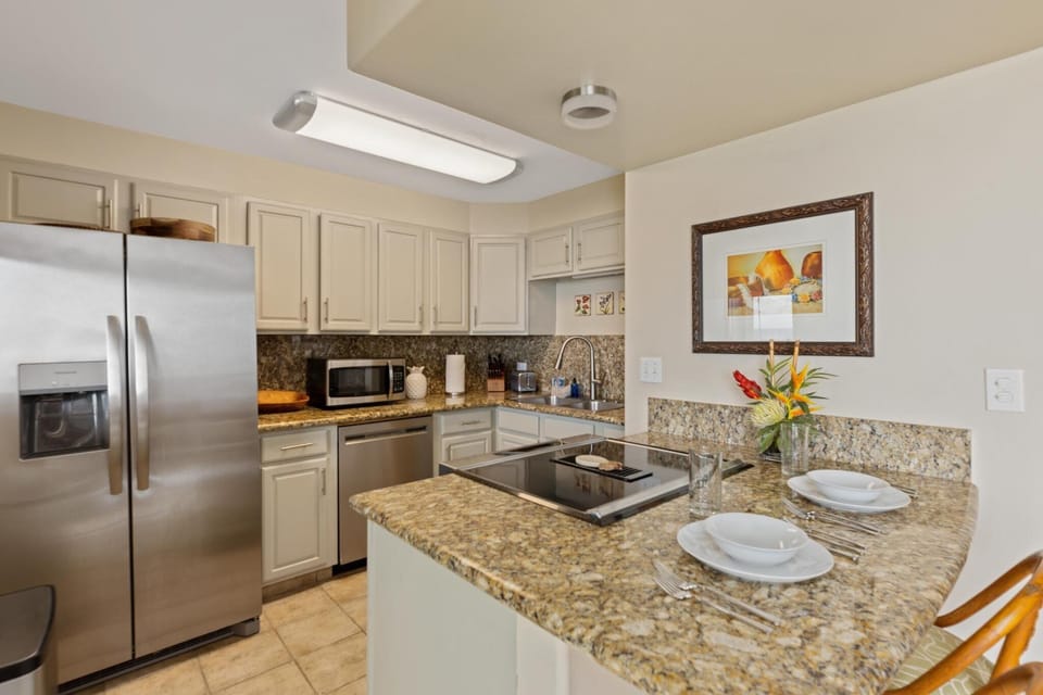 Cook in style with this modern, fully equipped kitchen featuring granite countertops, stainless steel appliances, and a cozy breakfast bar with seating for two.