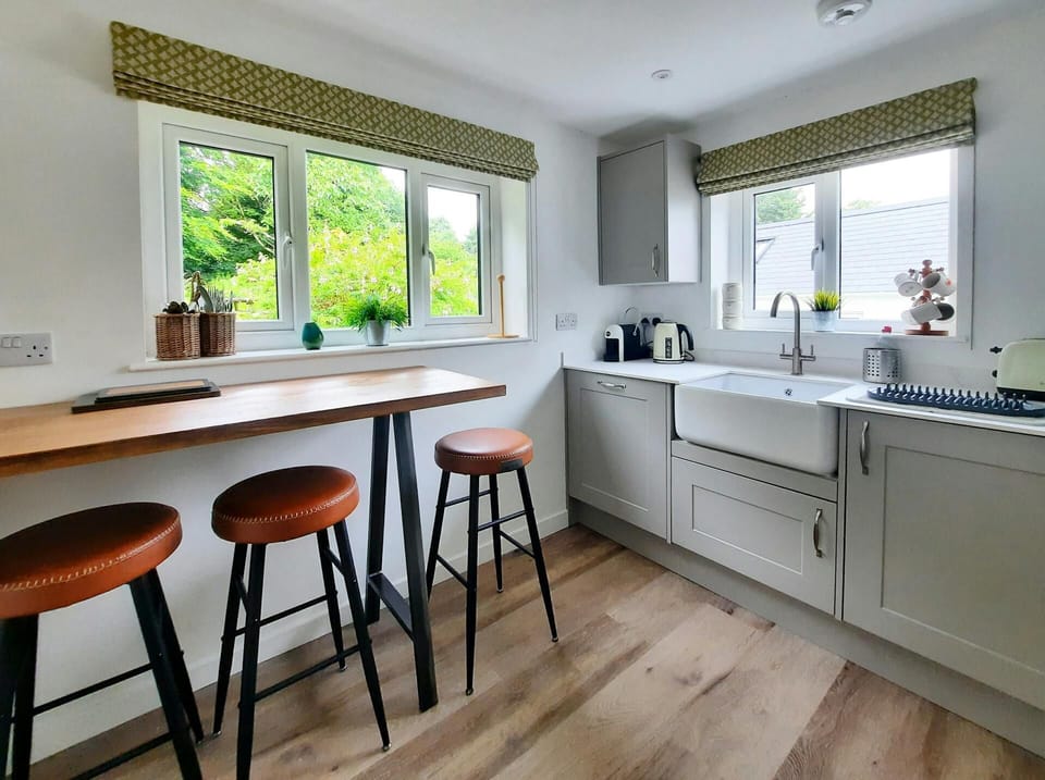 Kitchen with Belfast sink, kettle, toaster and coffee maker, breakfast bar with three stools