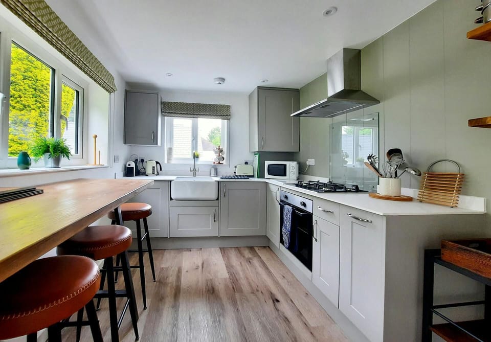 Kitchen with breakfast bar and three stools, built-in electric oven, gas hob, microwave, kettle, coffee maker and toaster