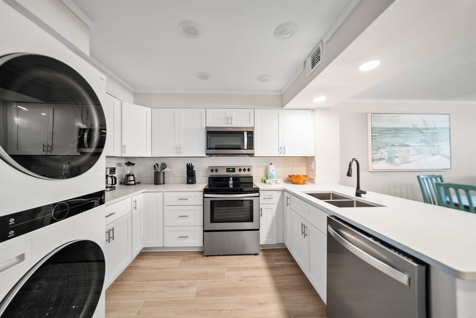 Your modern kitchen awaits with gleaming appliances, pristine white counters, and a convenient washer-dryer combo for effortless meal prep and laundry.