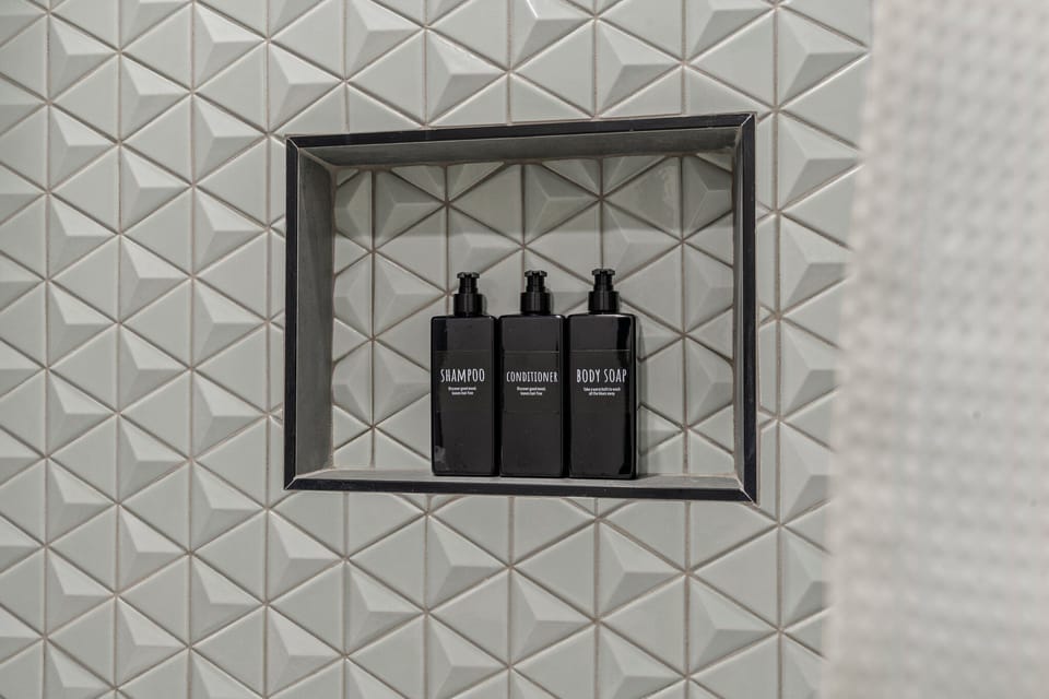 Pamper yourself with the luxurious amenities provided in this space. You'll appreciate the premium shampoo, conditioner, and body soap, perfectly displayed in a stylish nook, adding a touch of elegance to your daily routine.
