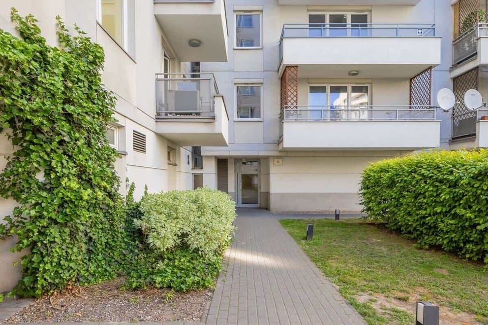 A ground-level view of the apartment complex, surrounded by manicured bushes.

