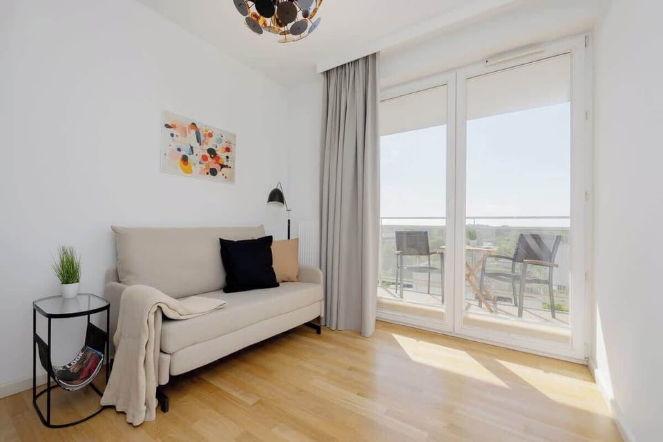A third bedroom with light curtains, minimalist decor, and access to a balcony.

