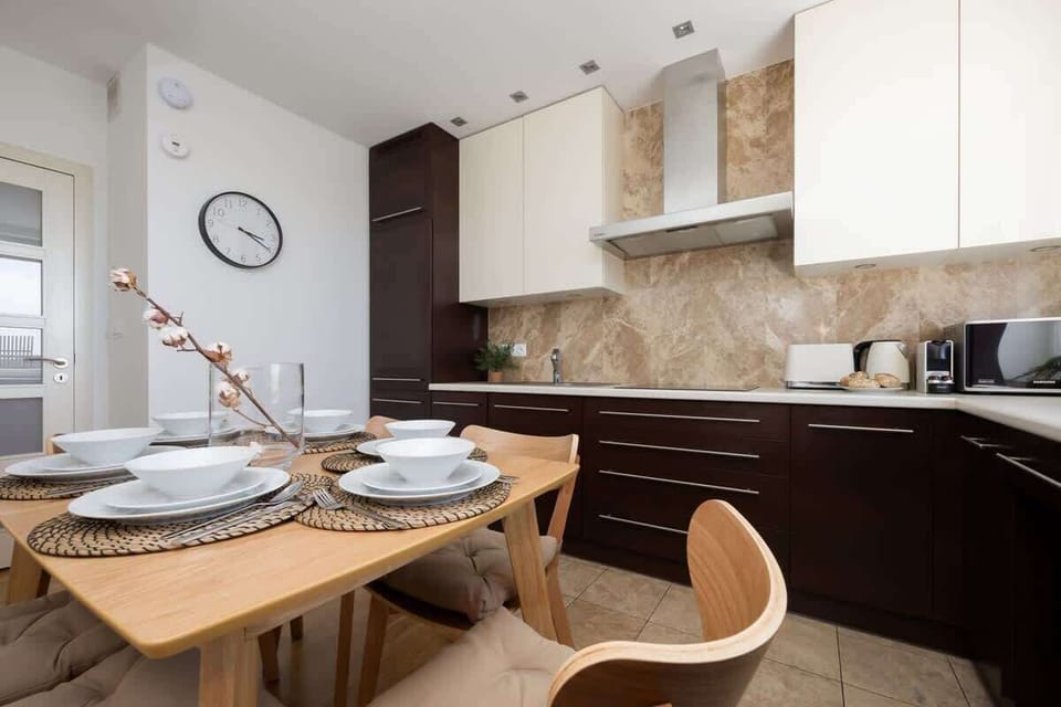 A second kitchen view with light cabinetry, dark countertops, and a matching dining area.

