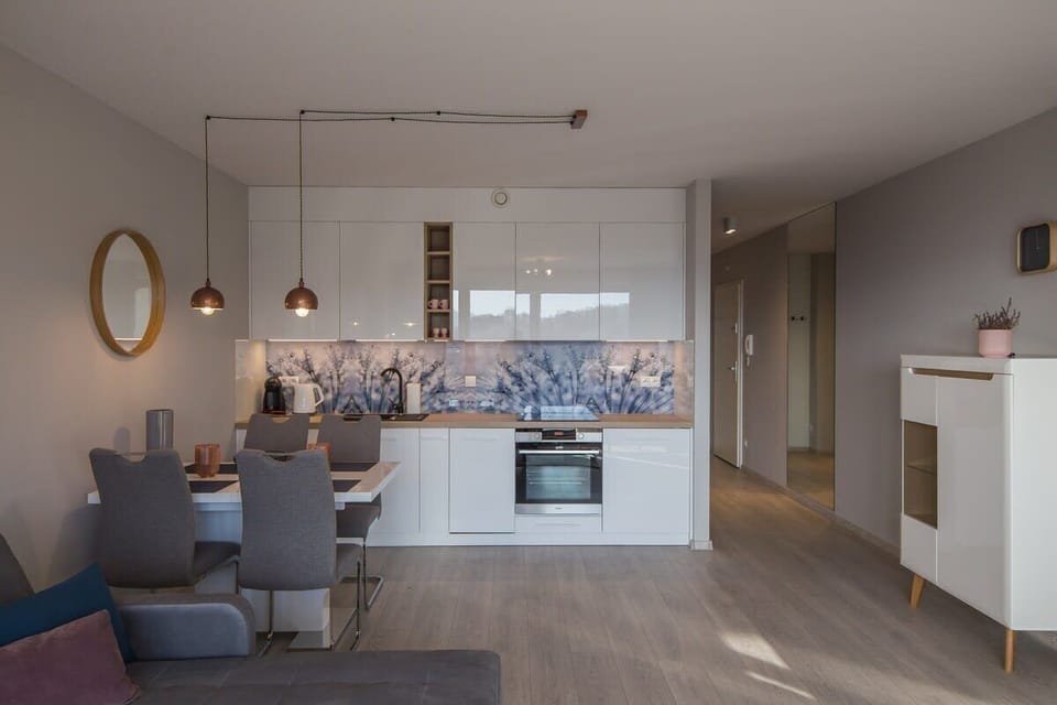 A spacious living space blending kitchen, dining, and lounge areas with stylish lighting and pale wood flooring.






