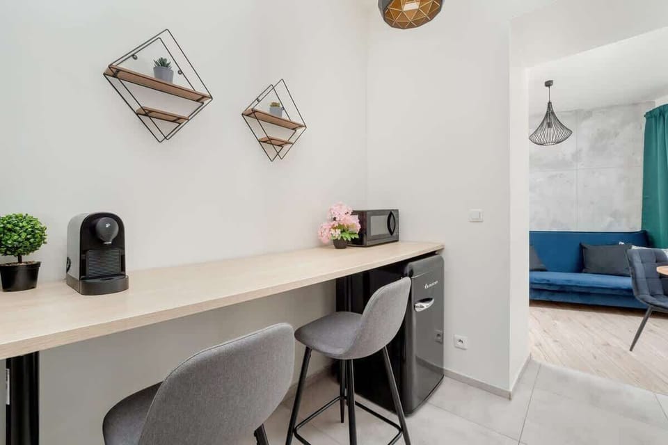 A light-toned desk setup with a coffee machine, wall-mounted art, and functional work area.

