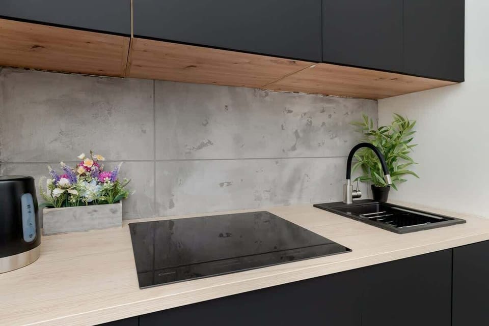 A modern kitchen corner with a sleek black countertop and natural wood accents.

