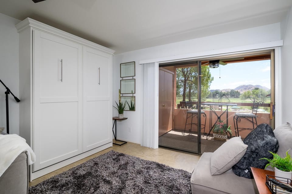 Murphy bed cabinet stands opposite sliding glass doors opening to a balcony with mountain views.