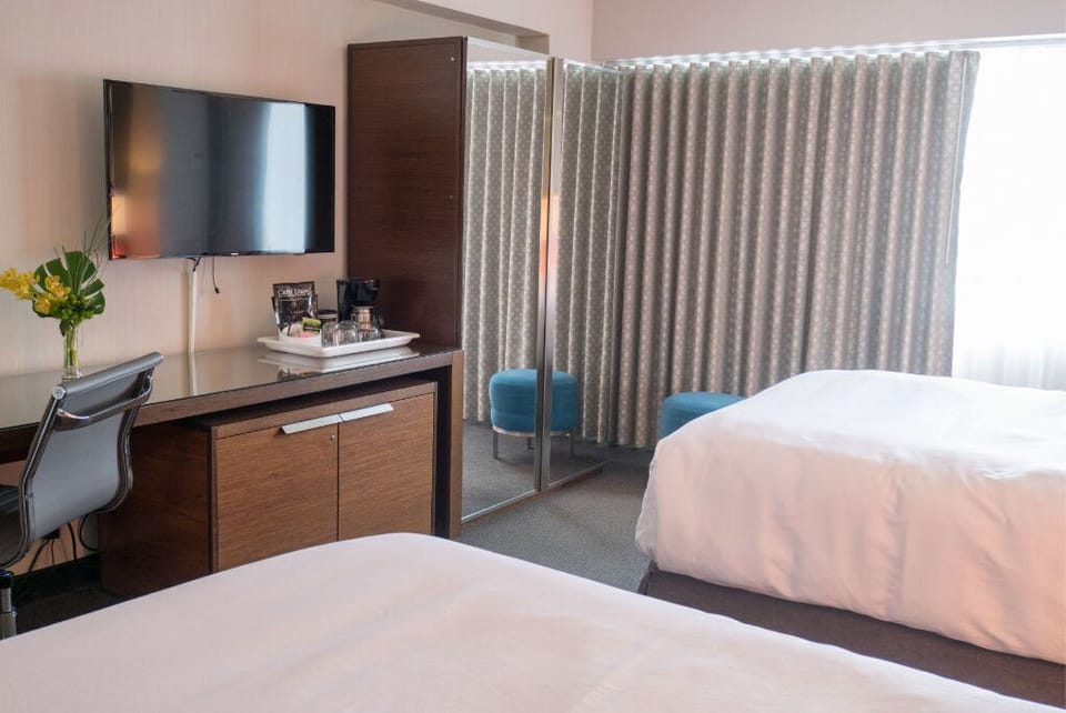 Streamlined and welcoming room featuring two beds and a convenient workspace, perfectly suited for both leisure and business travelers.