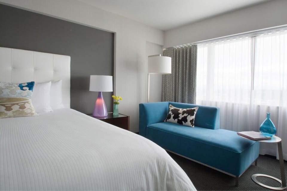 Modern and airy bedroom featuring a tranquil color palette and expansive windows, ideal for a peaceful retreat from the urban hustle.