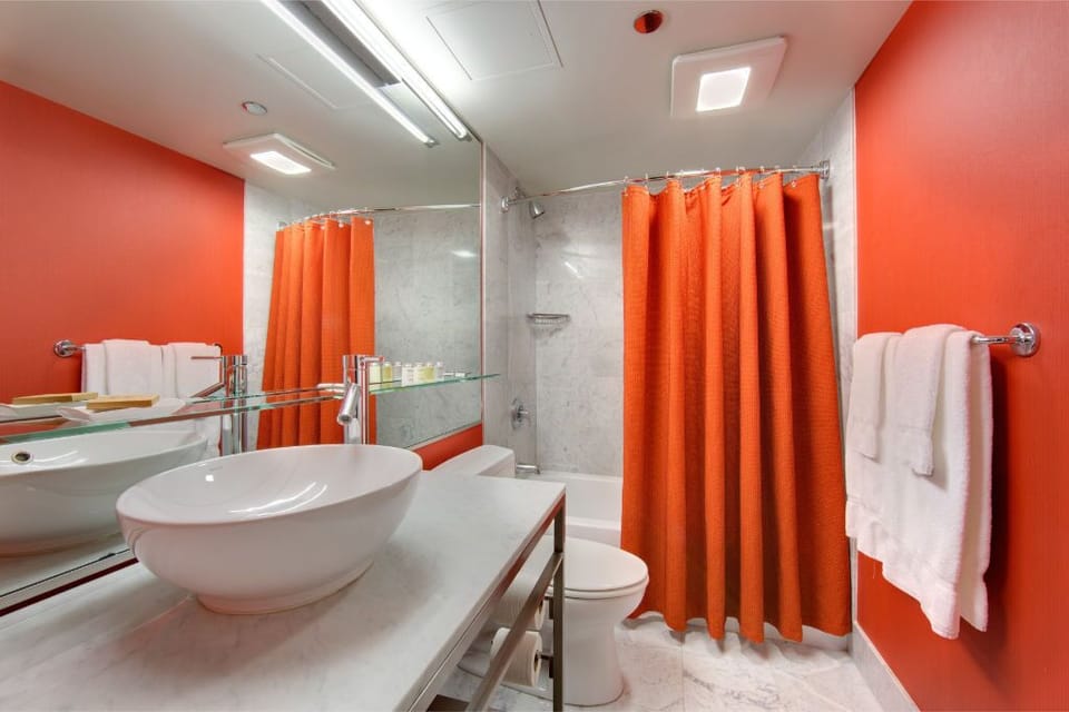 Refresh in our sleek, modern bathroom with striking red accents, designed for a serene and revitalizing experience.