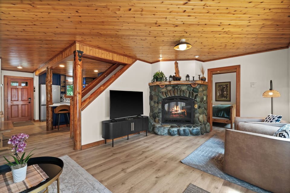 Rustic stone fireplace and open living space with wood accents and smart TV