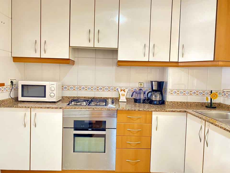 Kitchen open to the living room with breakfast bar, modern and equipped with all the necessary appliances for your comfort. Perfect for preparing your meals while you share moments with your family and friends in a functional and cosy space.
