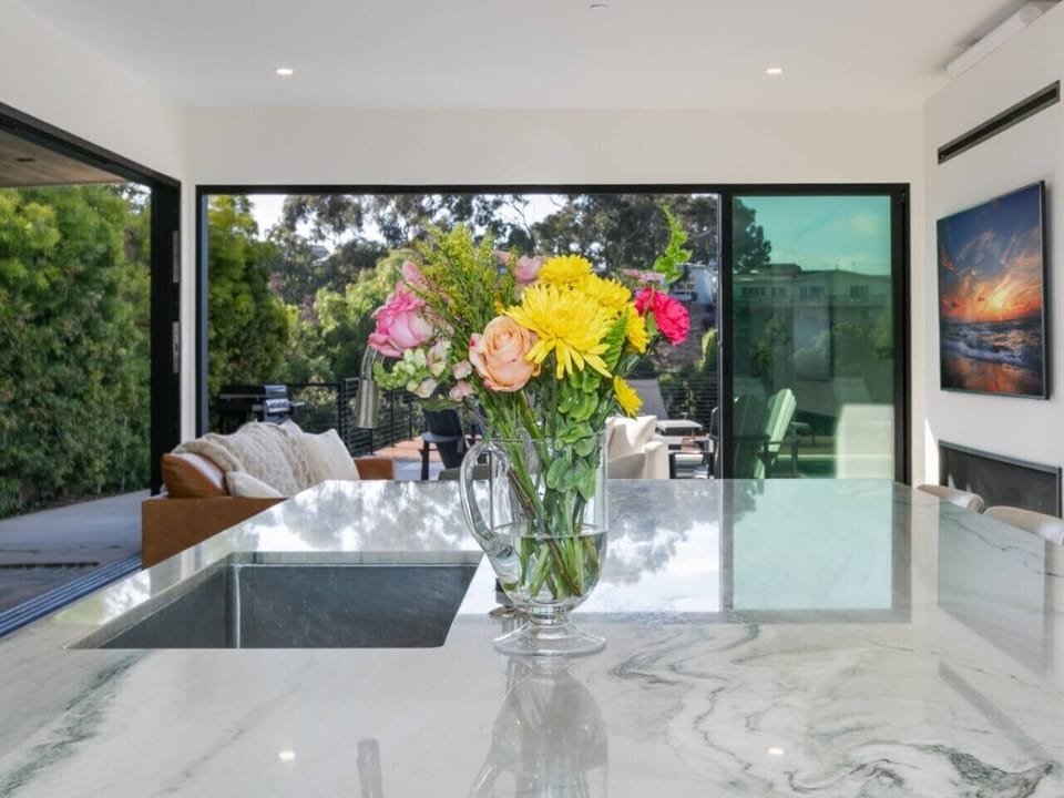 After lounging on the patio, step into a haven of relaxation in the living area, featuring a huge sofa and a round couch, with a large flat-screen TV above the indoor fireplace.