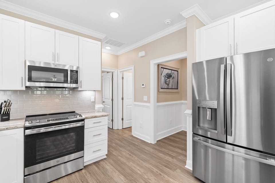 Your modern kitchen features stainless steel appliances, pristine white cabinetry, and warm wood floors for effortless meal preparation.