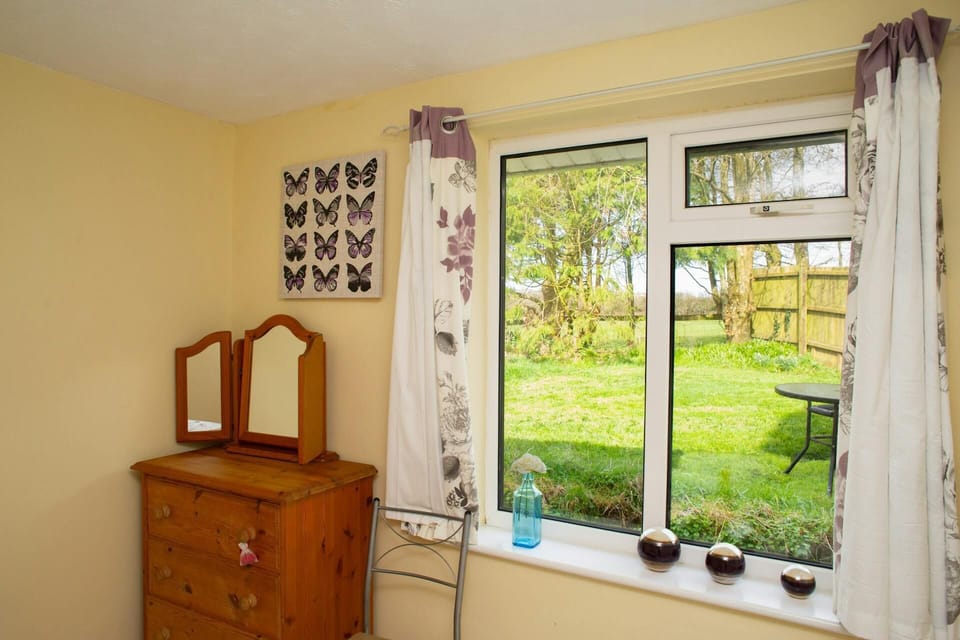 Bedroom with chest of drawers with mirrors. Butterfly wall art. Ornaments on windowsill