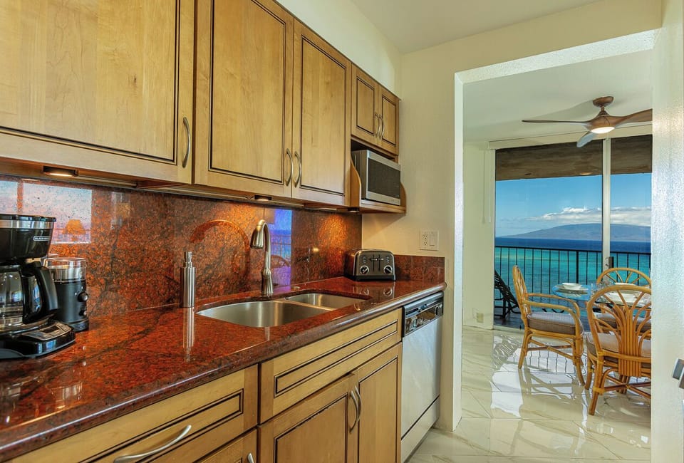 Step into your fully equipped kitchen where morning coffee meets stunning ocean vistas—prepare your meals while gazing at endless turquoise waters through the open dining area.