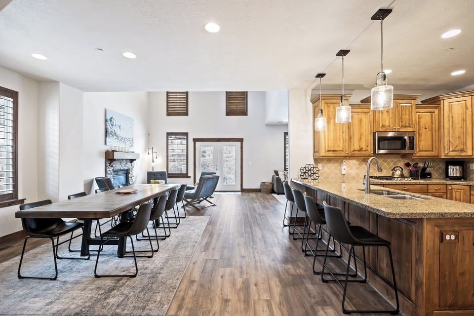 - Spacious dining and kitchen area with wood floors  
- Long dining table plus breakfast bar with seating  
- Open layout perfect for gatherings and shared meals