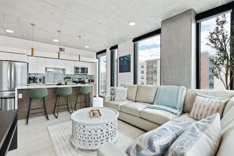 Large open living room, kitchen and dining with ceiling to floor views of downtown Salt Lake City.