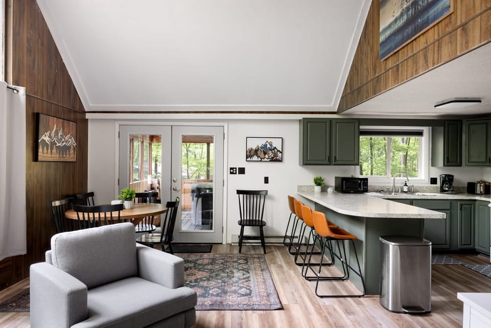 Open-concept kitchen and dining area with green cabinetry and a cozy seating space.
